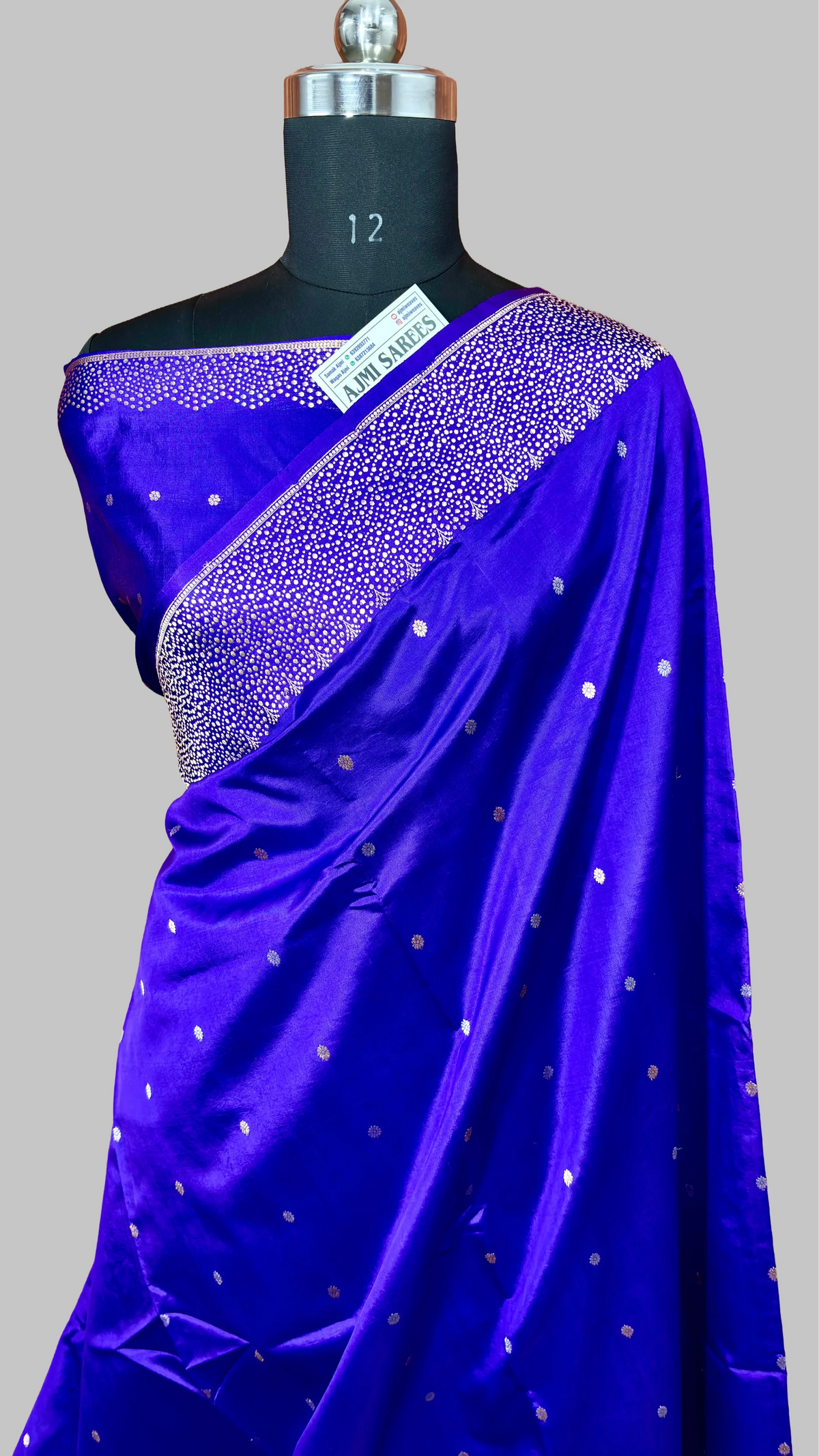 Royal blue saree with silver polka dots and embellished border displayed on mannequin