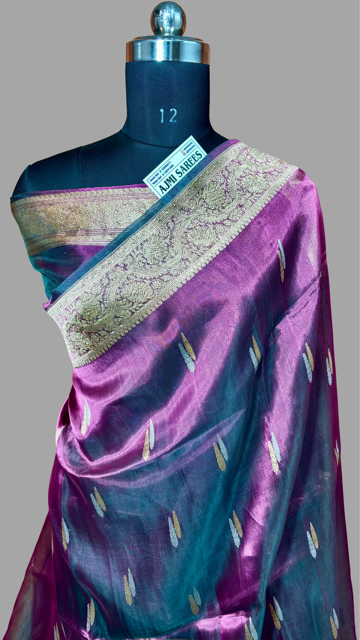Purple and teal silk saree with gold zari border and woven motifs displayed on mannequin
